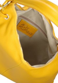 Geel leren handtas met een textuurafwerking, voorzien van een ritssluiting, beige voering en een label met de tekst "Made in Italy."