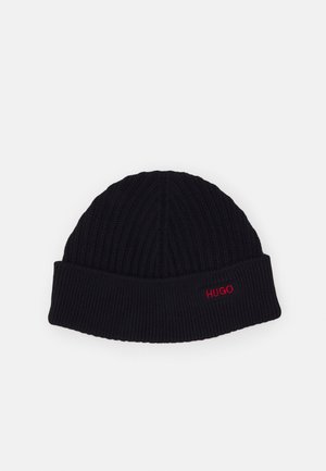 Bonnet en maille côtelée noire avec revers plié, arborant un petit logo rouge "HUGO" brodé sur le devant du revers.