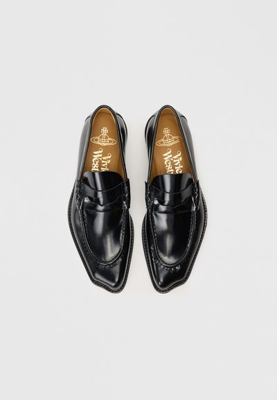 Mocassins de couro preto com bico fino, apresentando um acabamento suave e costura decorativa ao longo das bordas. Sola interna castanha com logotipo.