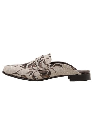 Vetoketjulla varustettu loafer-kenkä, jossa on beige kangas, jossa on tummanruskea kukka-ommeltaideteos ja matala musta korko, esitetty sivuprofiilissa.