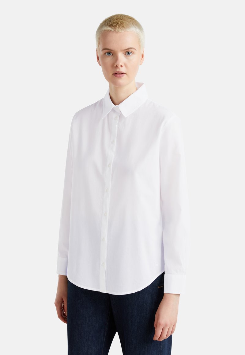 Bílá košile s knoflíky, klasickým límcem, dlouhými rukávy a zakřiveným lemem, vyrobená z hladké bavlněné tkaniny.