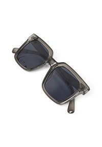Lunettes de soleil carrées avec des verres foncés et une monture en plastique gris fumé. Elles présentent des branches épaisses avec un branding discret sur la charnière.