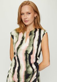 Ärmelloses Kleid mit V-Ausschnitt, das ein Aquarellmuster in den Farben Rosa, Grün und Schwarz auf einem glatten Stoff zeigt.