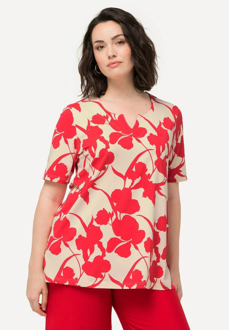 Top floreale a maniche corte con sfondo crema, caratterizzato da audaci motivi floreali rossi e un sottile design a V. Tessuto liscio e leggero.