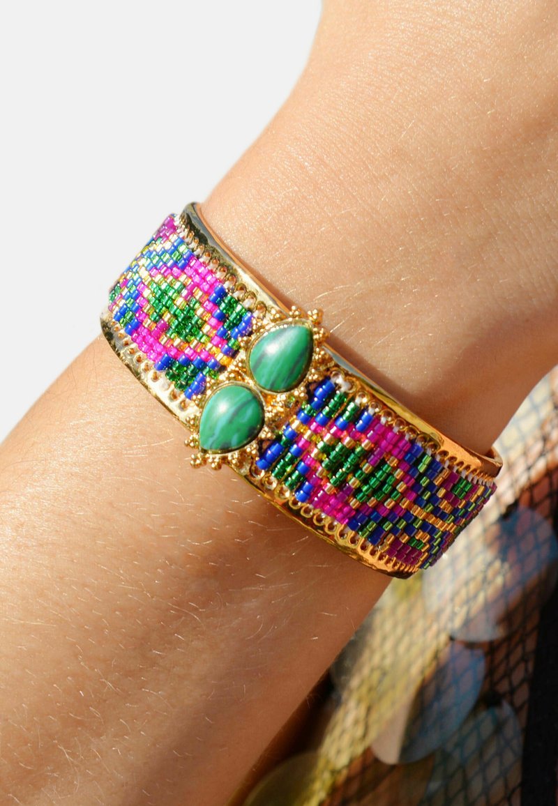 Bracelet en perles multicolores avec une base en or, comportant deux gemmes ovales vertes au centre. Motif texturé et vibrant tout au long.