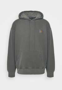 Felpa grigia con cappuccio, tasca frontale tipo kangaroo, cappuccio con cordoncino, polsini a costine e piccola toppa quadrata con logo sul petto.
