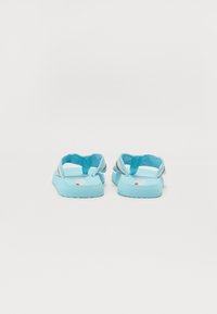 Flip-flops de culoare albastru deschis, cu tălpi din cauciuc texturat și curele împletite cu accente multicolore. Design minimalist, cu un profil plat.