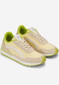 Light yellow sneakers with green accents, suede and fabric combination, rounded toe, lace-up design, featuring a white logo tag on the tongue.
