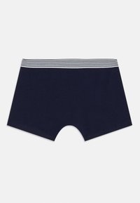 Mørkeblå boxershorts til gutter med en hvit og svart stripete elastisk midjebånd, lagt flatt på en hvit bakgrunn.