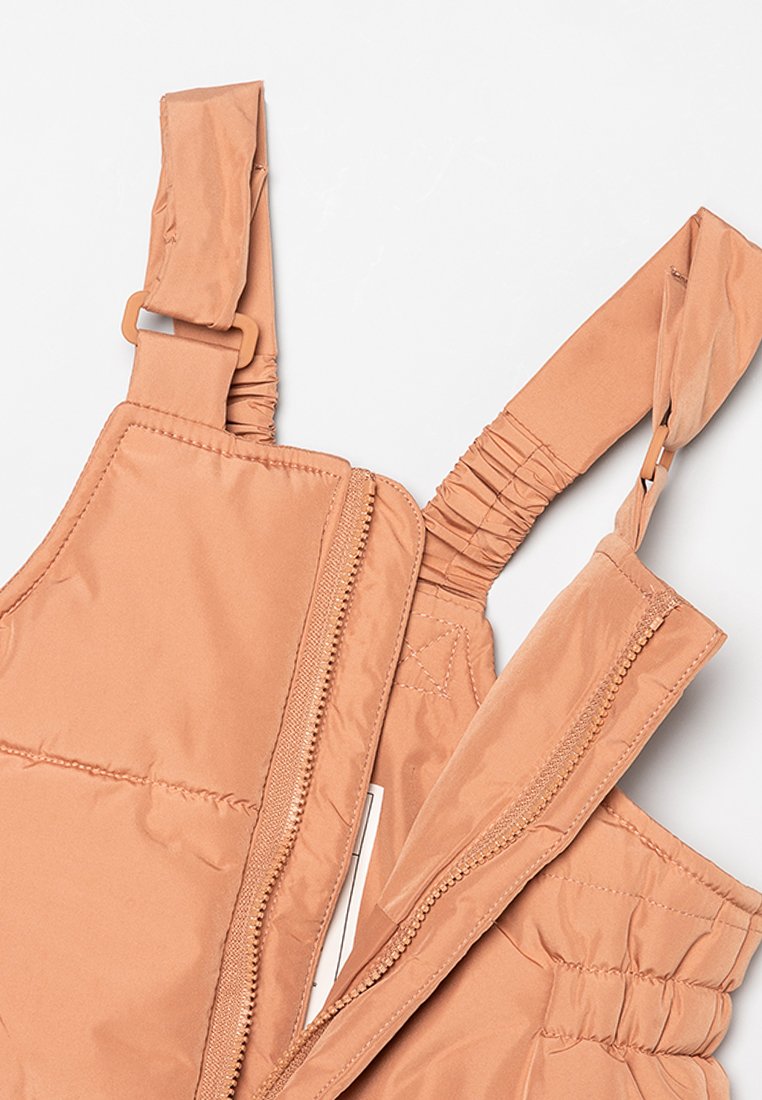 Helle braune gepolsterte Winteroveralls mit verstellbaren Schulterträgern und einem vorne teilweise geöffneten Reißverschluss auf einem weißen Hintergrund.