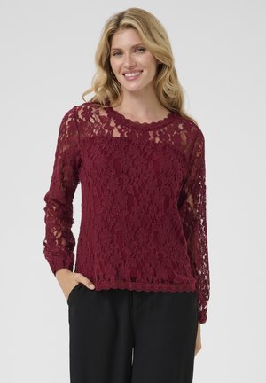 Top en dentelle bordeaux avec de longues manches transparentes et un col à bords festonnés. Présente des motifs floraux complexes et une coupe ample.