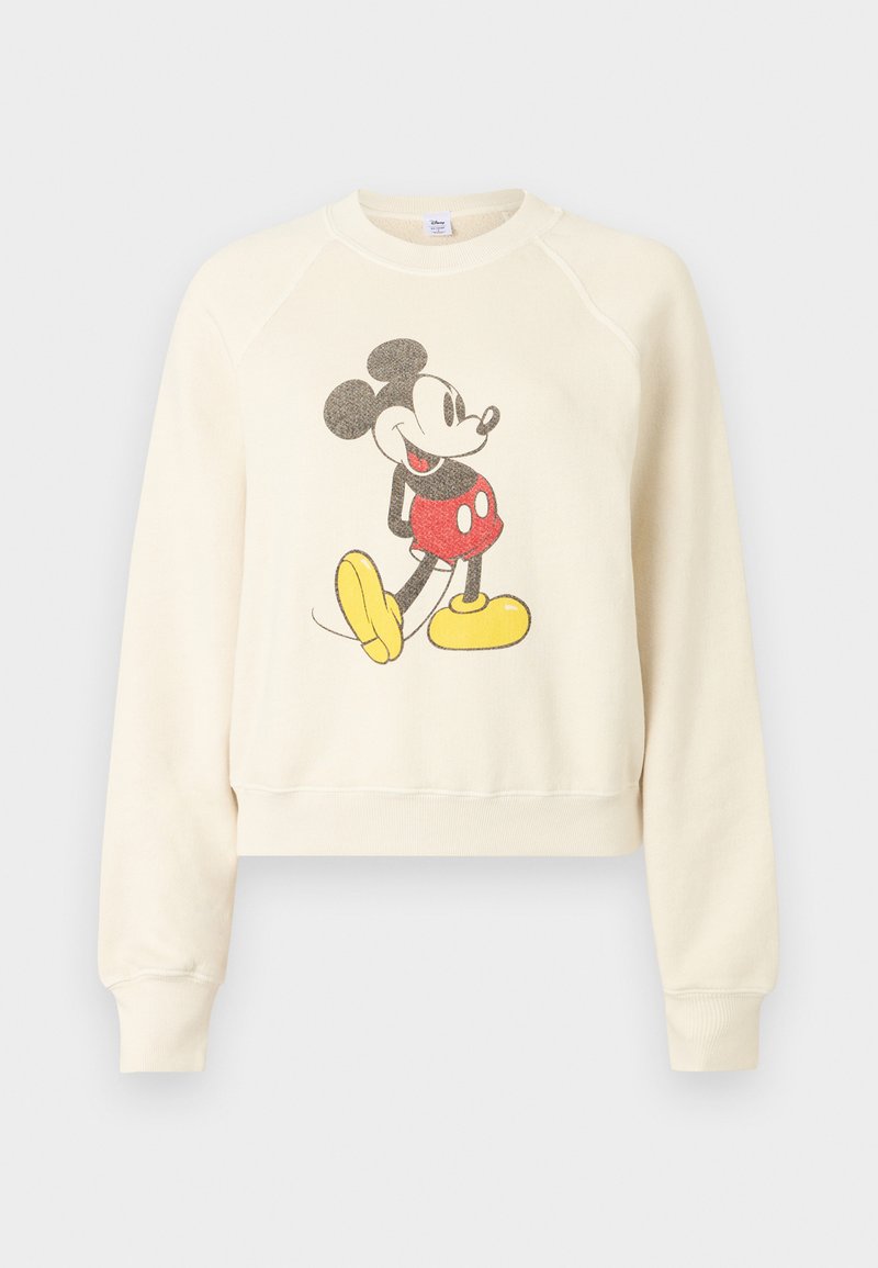 Sweat-shirt couleur crème avec un graphique vintage de Mickey Mouse portant un short rouge et des chaussures jaunes à l'avant.