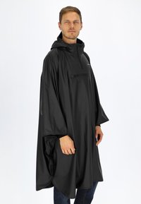 Svart vattentät poncho med huva, med en framfick med dragkedja, löst sittande och slät textur. Funktionell design för utomhusbruk.