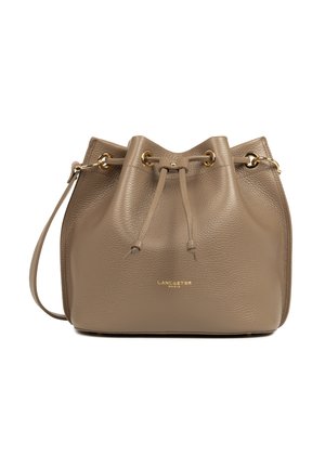Sac seau en cuir taupe avec une bandoulière réglable, œillets dorés, fermeture à cordon et logo "Lancaster Paris" sur le devant.