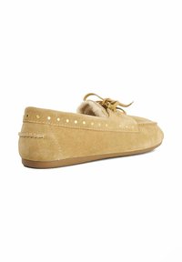 Tan suede moccasin with a rounded toe, lace tie, and gold stud accents along the side. Soft interior lining for comfort. Flat rubber sole.