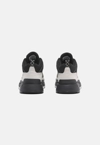 Svarta och grå sneakers med en slät läder- och textilöverdel, vadderad krage och tjock gummisula, som visar en modern design.