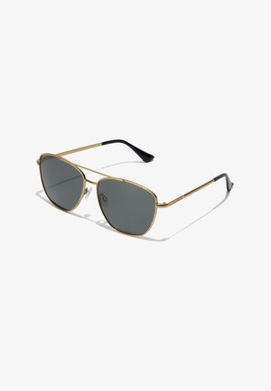 Gafas de sol de metal dorado con lentes grises, de forma ovalada, con montura delgada y puntas negras en las varillas. Cuentan con almohadillas nasales ajustables para mayor comodidad.