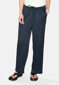 Navy blue wide-leg pants made of textured fabric, featuring an elastic waistband with a drawstring and side pockets.