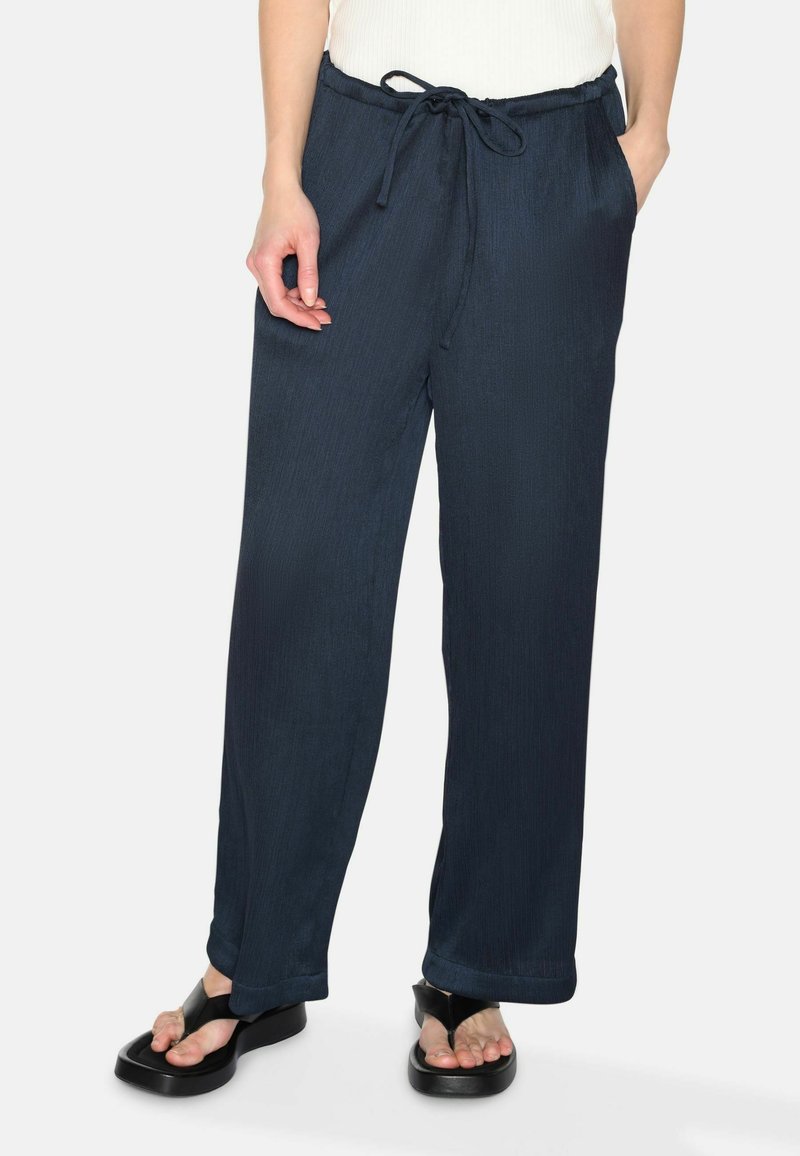 Navy blue wide-leg pants made of textured fabric, featuring an elastic waistband with a drawstring and side pockets.