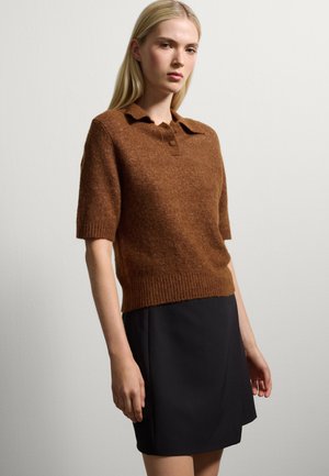 Maglione corto a maniche corte in misto lana marrone con colletto e orlo a coste, abbinato a una gonna nera al ginocchio.