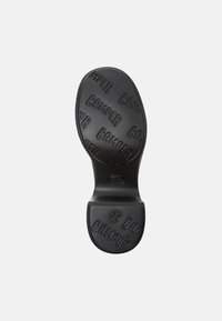 Sole in gomma nera con un motivo impresso che riporta "Camper" e la misura "38". Forma arrotondata con superficie texturizzata per una migliore aderenza.