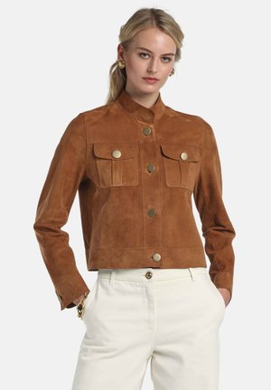 Brązowa krótka kurtka z zamszu z kołnierzem typu mandarynka, z przodu zapinana na guziki oraz z dwoma kieszeniami na piersi ozdobionymi guzikami w złotym kolorze.