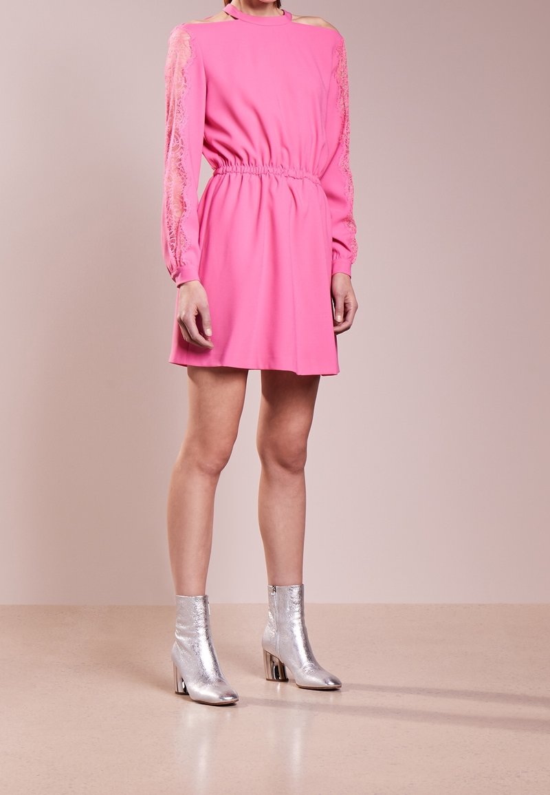 Fuchsiaklänning med långa spetsärmar, elastisk midja och öppna axlar; ihop med silverfärgade ankelskör med blokkhäl.