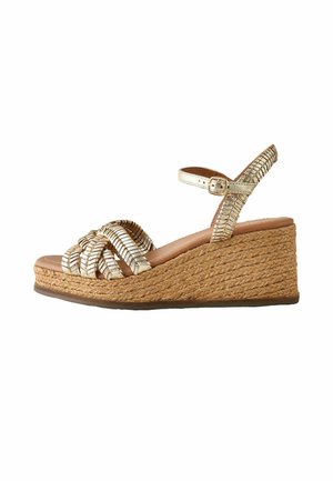 Beżowe sandały na koturnie z plecioną jutową platformą, metalowym paskiem na kostkę z klamrą oraz plecionymi przednimi paskami.