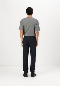 Grå bomulds T-shirt med korte ærmer, parret med marineblå plaid bukser. Bukserne har baglommer og bæltetasker, båret med sorte sko.