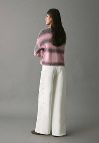 Suéter de punto con rayas rosas y grises; pantalones anchos blancos con detalles de botones de lado; textura suave; ajuste casual.