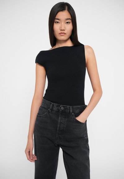 Sort ribbet tanktop med en asymmetrisk halsudskæring, båret med højttaljede mørk denim jeans med lige ben og sidelommer.