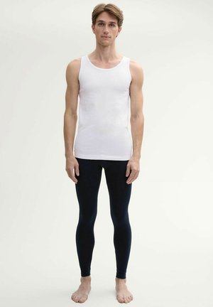 Weißes Baumwoll-Top, kombiniert mit figurbetonten, dunkelblauen Leggings; minimalistisches Design mit glatter Textur und klaren Linien.