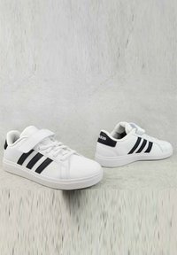 Sneakers bianchi realizzati in materiale sintetico, con una texture liscia, tre strisce nere e una fascia in Velcro per una vestibilità sicura.