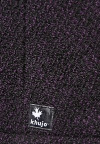 Gorro Khujo en negro y púrpura oscuro, con un patrón de punto texturizado y un parche de logo con un diseño de hoja.