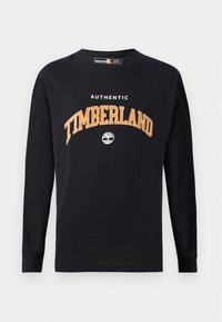 Crna majica dugih rukava sa bijelim i narančastim natpisom i logotipom "AUTHENTIC TIMBERLAND". Mekani pamuk s okruglim izrezom.
