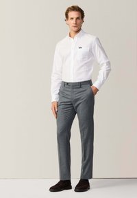 Witte overhemd met knopen en een borstzak, grijze op maat gemaakte broek met een gestructureerde afwerking en brown suede schoenen.