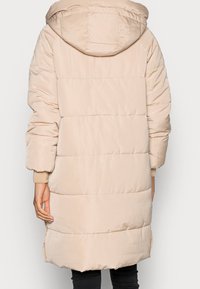 Beige puffy jakke med hætte, quiltet design, elastiske manchetter, sideslids og en mellemlang pasform. Glat, blankt materiale.