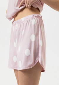 Shorts en coton rose avec de grands pois blancs, dotés d'une ceinture élastique et d'évents latéraux pour faciliter les mouvements.