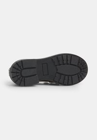 Suela de goma negra con un patrón de superficie texturizada, que presenta un diseño segmentado para agarre y durabilidad, sección de talón plana y ligeramente elevada.