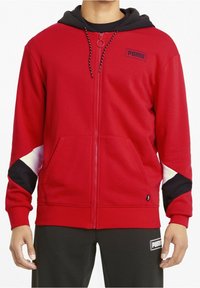 Rode hoodie met rits en een zwarte capuchon, voorzien van wit en zwarte accenten. Zacht materiaal, voorzakken en een klein Puma-logo op de borst.