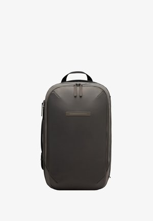 Sac à dos gris au design épuré, texture lisse, avec deux tirettes de fermeture éclair et un panneau avant minimaliste. Comprend une poignée supérieure et une poche latérale.