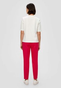 White short-sleeve t-shirt with a round neckline, paired with bright pink slim-fit trousers and white sneakers. Smooth fabric, minimalistic design.