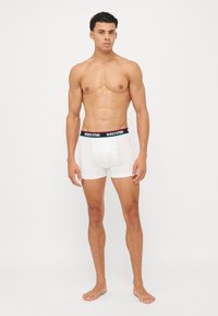 White boxer shorts with a black waistband featuring red text. The shorts have a snug fit and a smooth, cotton-like texture.