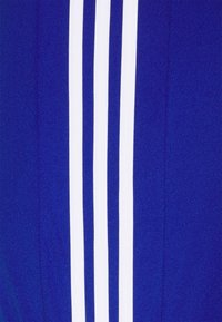 Zils sporta krekls ar trim vertikālām baltām svītrām. Auduma virsma ir gluda ar vieglu spīdumu.