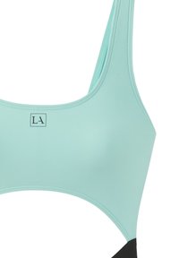 Sportiva di un leggero verde acqua con una superficie liscia, decorata con dettagli neri e un piccolo logo al centro. Spalline spesse con scollatura rotonda.