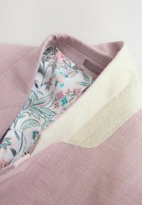 Rózsaszín blézer gallérral, krémszínű filc könyökpárnával, belső részén pasztell rózsaszín, zöld és kék tónusú virágos béléssel.