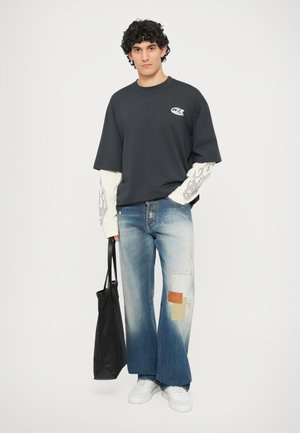 Svart bomulls T-skjorte med kort erme og grafisk detalj. Lys blå denim jeans med lappearbeid og frynsete kanter. Svart totebag.