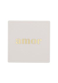 Targa rettangolare bianca con la parola in minuscolo "amor" in oro embossato al centro della superficie.