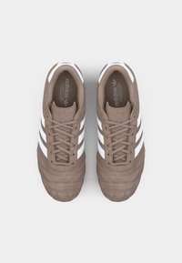 Brown suede sneakers with white three-stripe design, textured toe cap, and laces. Interior features logo and cushioned insole.