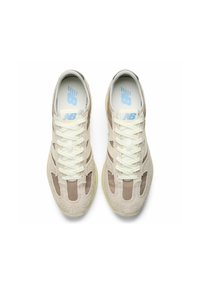 Hellbeige Sneaker mit Obermaterial aus Wildleder und Nylon, weißen Schnürsenkeln und vergilbter Gummisohle. Verfügt über ein belüftetes Design und blaue Logo-Akzente.